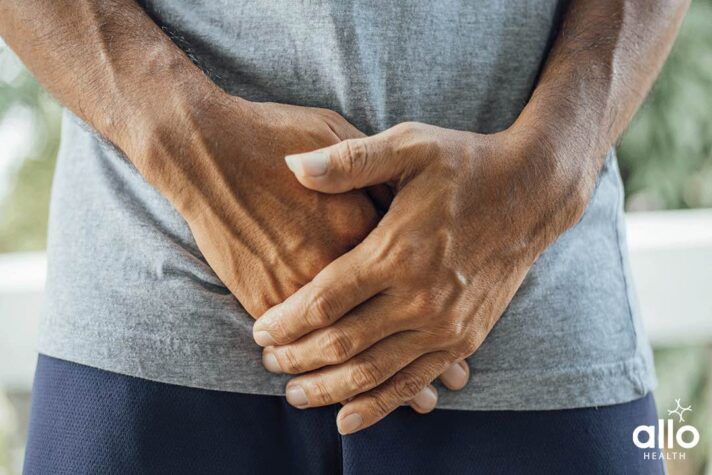 man suffering with Urinary Tract Infection and holding lower abdomen due to pain, prevention of gonorrhea in hindi