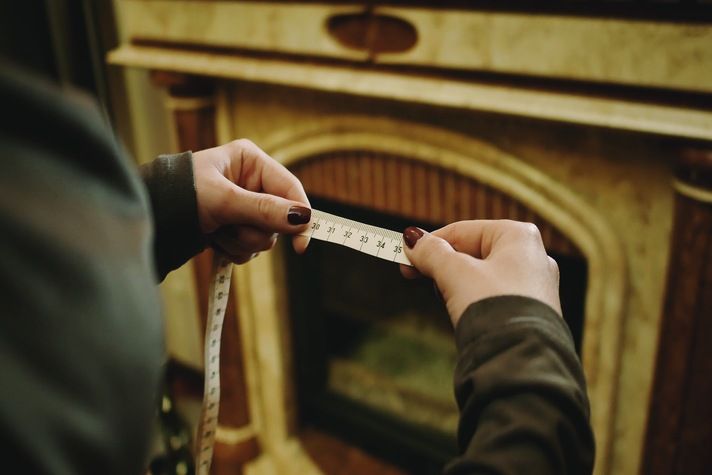 A loosely coiled measuring tape on a wooden table, representing the teasing and size comparison aspect of SPH, a popular erotic humiliation kink involving consensual roleplay