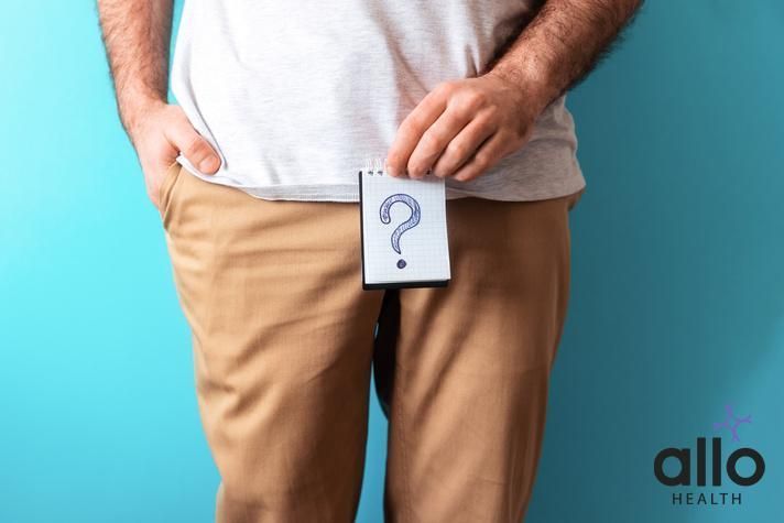 A man in beige jeans holds a notepad with question mark. Close up. Blue background. The concept of artificial insemination and impotence. does masturbation affect muscle gains Does Urimax D Cause Impotence? Understanding Selective Impotence: Causes, Symptoms, and Treatments Penis Shrinking And Age-Related Sexual Changes